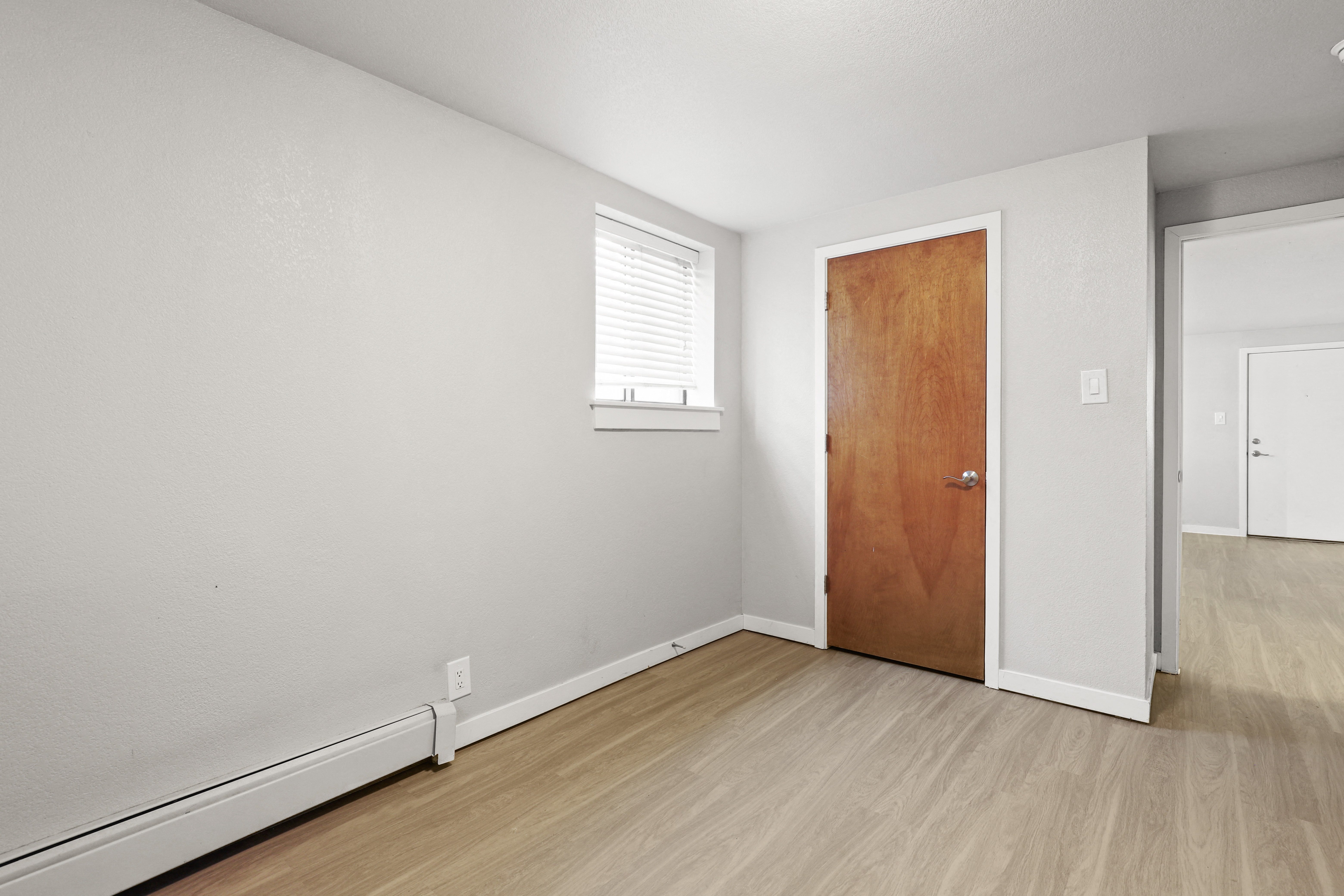 a bedroom with a door and a window and a wood floor